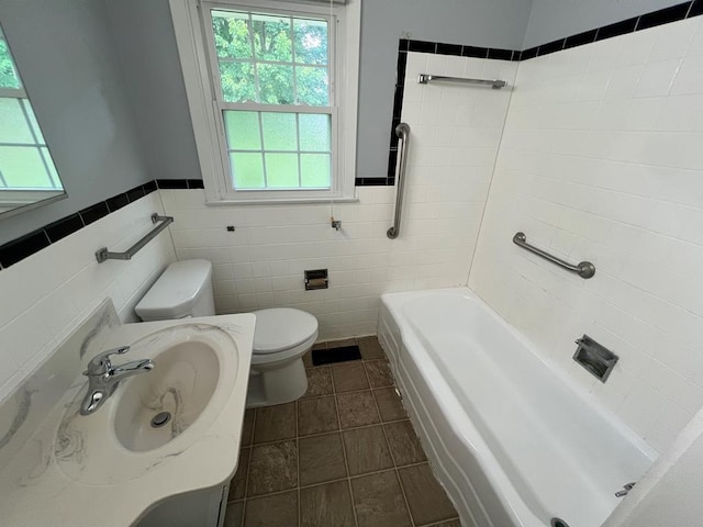 bathroom featuring a tub to relax in, tile patterned floors, sink, tile walls, and toilet