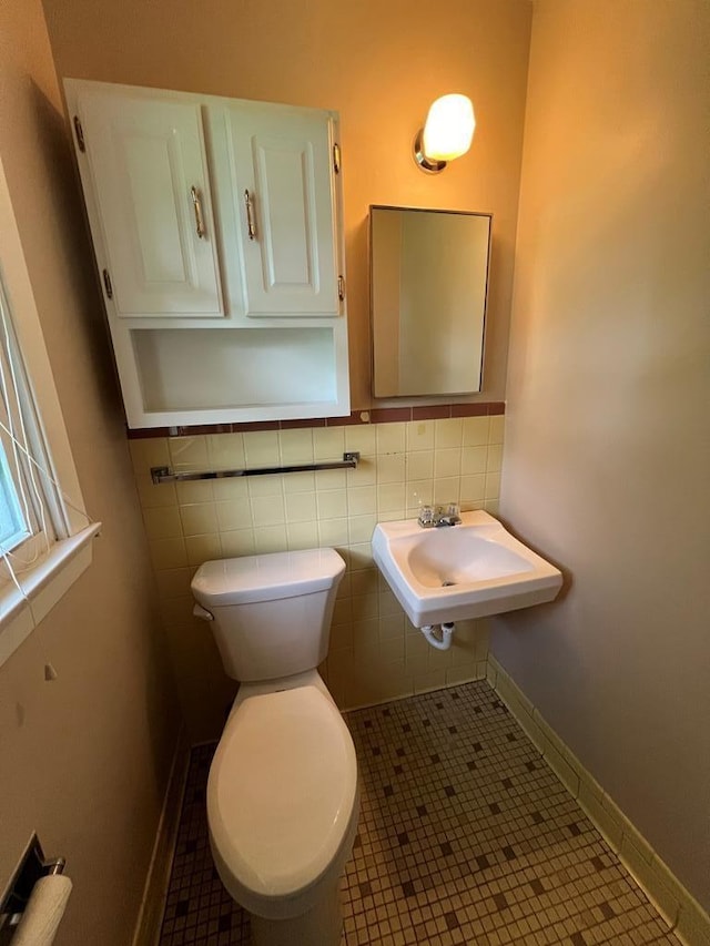 bathroom with tile patterned floors, toilet, sink, and tile walls