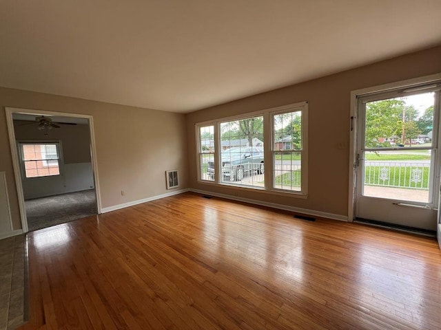 empty room with heating unit, light hardwood / wood-style floors, and ceiling fan