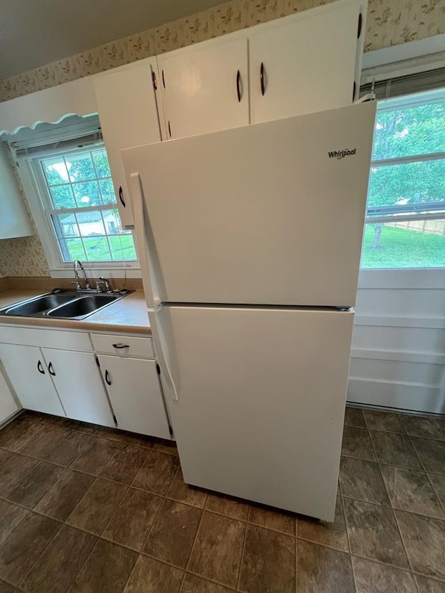 kitchen featuring white refrigerator, white cabinetry, a wealth of natural light, and sink