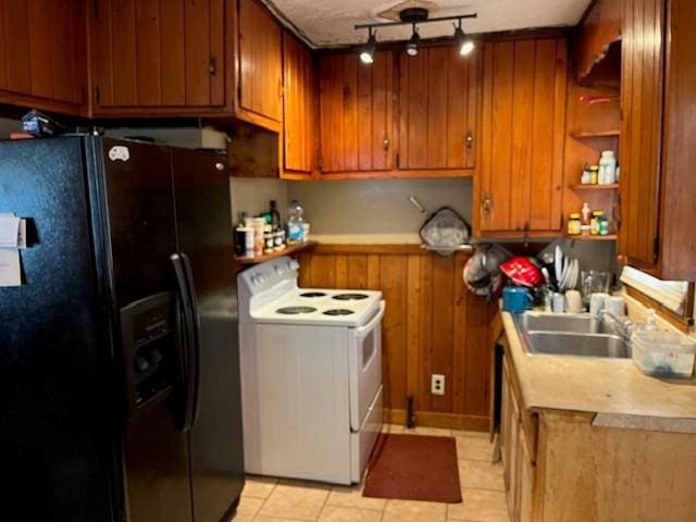 kitchen featuring black fridge, sink, light tile patterned floors, and electric range