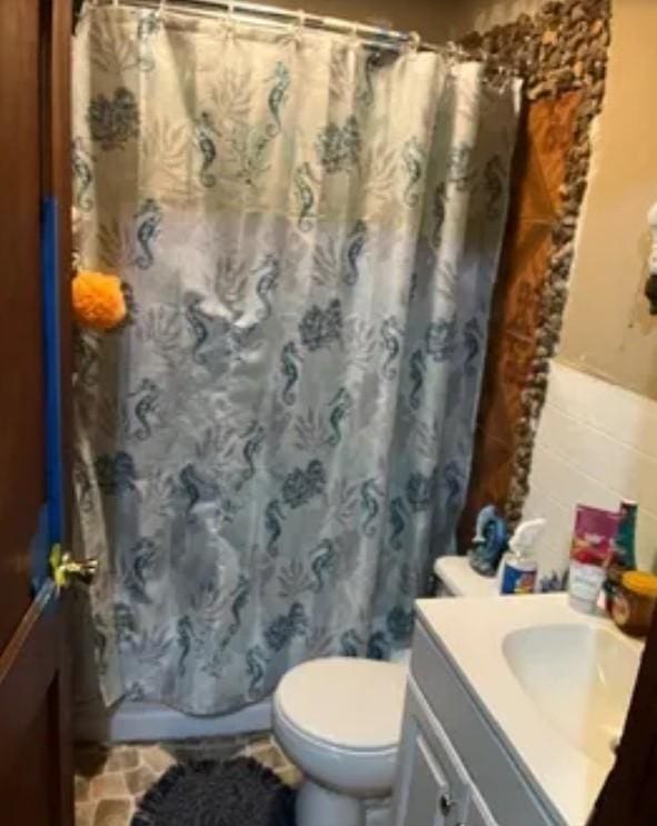 bathroom featuring a shower with curtain, vanity, toilet, and tile walls