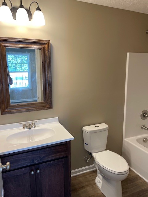 full bathroom with bathtub / shower combination, toilet, wood-type flooring, vanity, and a textured ceiling