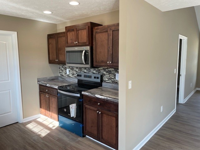 kitchen with a textured ceiling, stainless steel appliances, dark hardwood / wood-style flooring, and tasteful backsplash