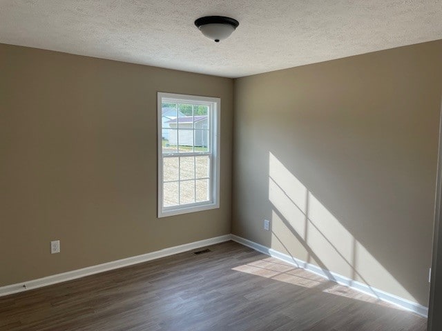 unfurnished room featuring hardwood / wood-style floors, plenty of natural light, and a textured ceiling