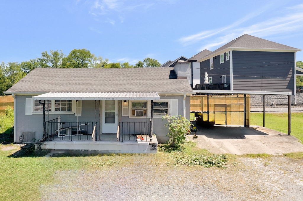 back of house with covered porch and a yard