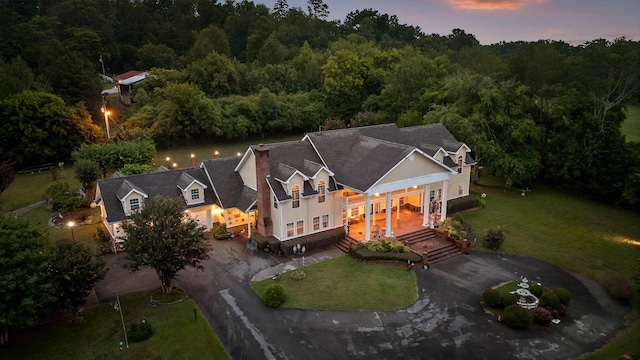 aerial view at dusk featuring a forest view