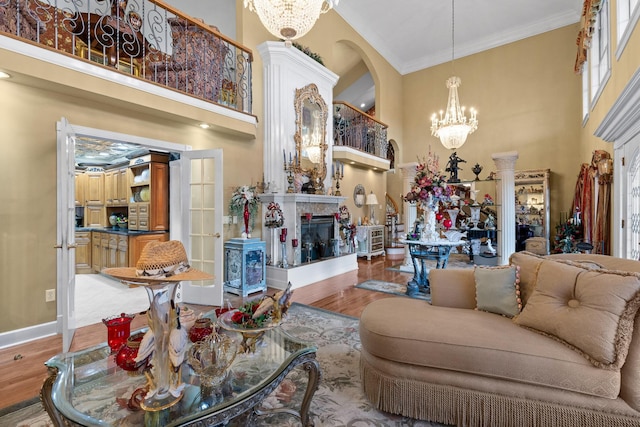 living room featuring an inviting chandelier, a towering ceiling, ornamental molding, and light hardwood / wood-style floors