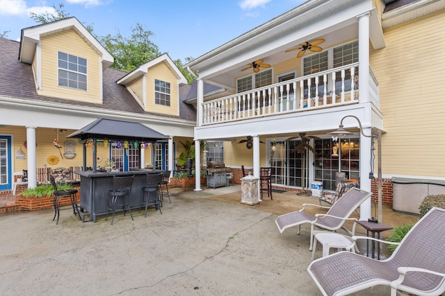 view of patio with ceiling fan, a grill, exterior bar, and a balcony