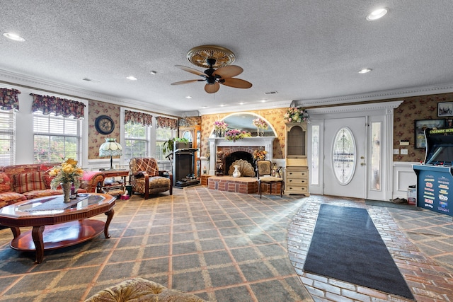 carpeted living room featuring ceiling fan, a fireplace, ornamental molding, and a textured ceiling