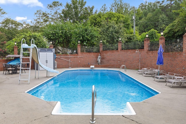 view of pool with fence, a water slide, a patio, and a fenced in pool