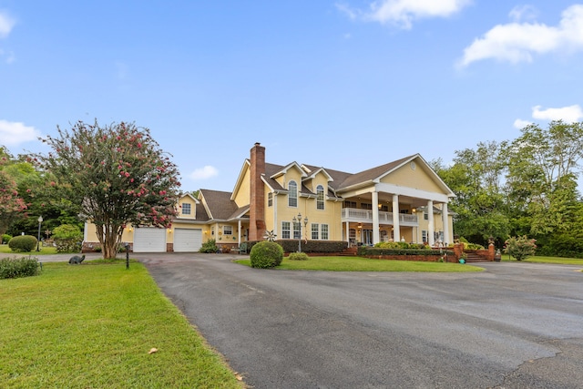 view of front of property with a garage, a front yard, and a balcony