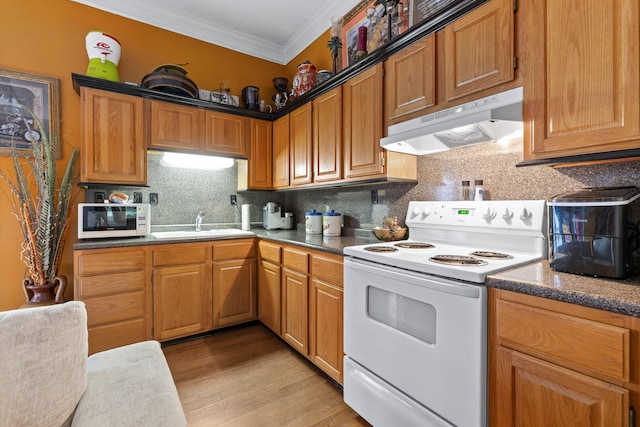 kitchen with backsplash, crown molding, under cabinet range hood, white appliances, and light wood-style flooring