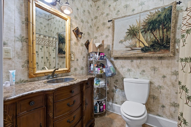 bathroom with vanity, baseboards, tile patterned floors, toilet, and wallpapered walls