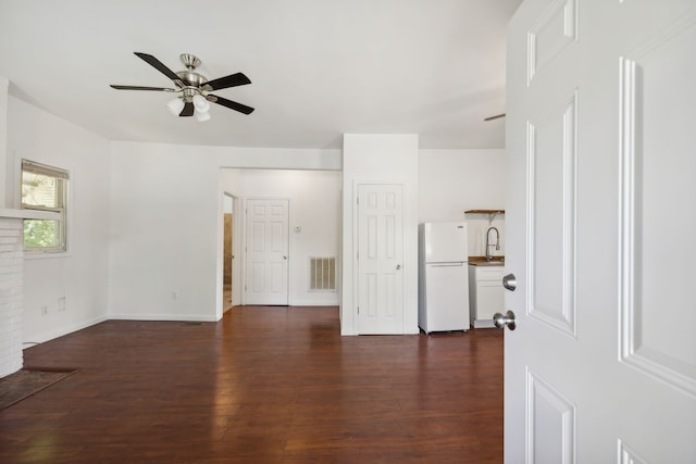 unfurnished living room featuring a brick fireplace, ceiling fan, and dark hardwood / wood-style flooring