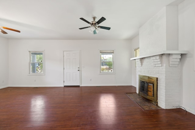 unfurnished living room with brick wall, dark hardwood / wood-style flooring, ceiling fan, and a fireplace