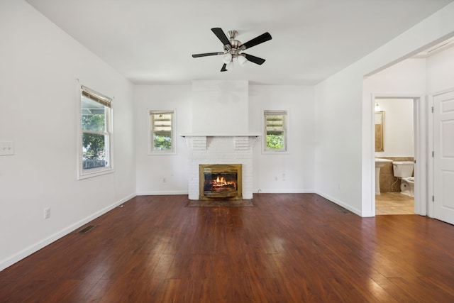 unfurnished living room featuring ceiling fan, hardwood / wood-style flooring, and a brick fireplace