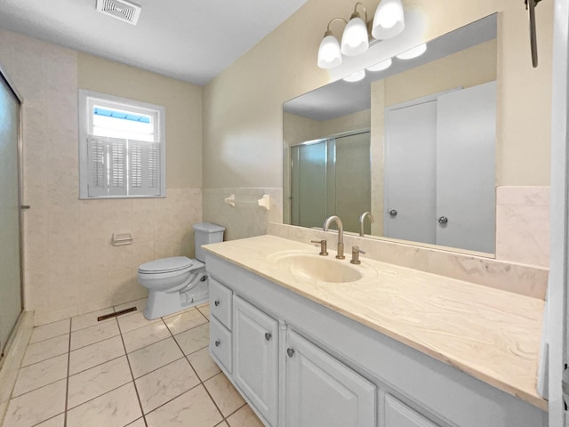 bathroom with tile patterned floors, an enclosed shower, vanity, tile walls, and toilet