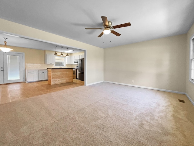 unfurnished living room featuring ceiling fan and light colored carpet