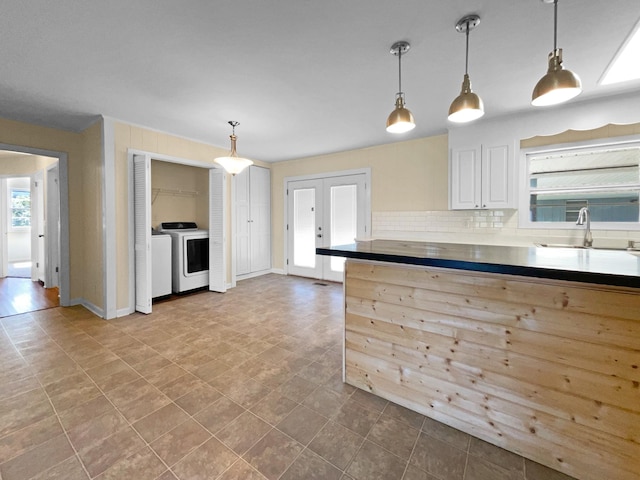 kitchen with backsplash, washing machine and dryer, hanging light fixtures, and sink