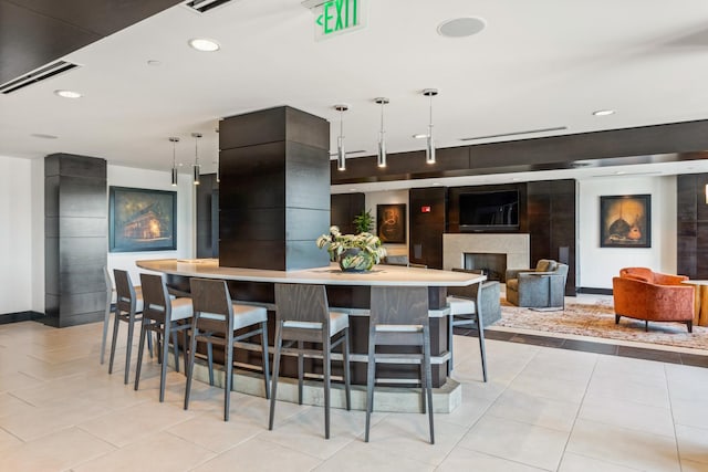 kitchen with pendant lighting, a kitchen breakfast bar, a large fireplace, and light tile patterned flooring