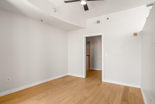 empty room featuring electric panel, light hardwood / wood-style floors, and ceiling fan