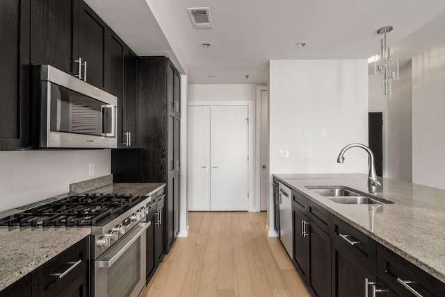 kitchen featuring decorative light fixtures, sink, light stone countertops, and stainless steel appliances