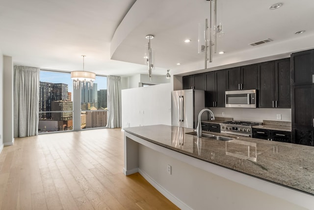 kitchen with pendant lighting, stone counters, an inviting chandelier, sink, and appliances with stainless steel finishes