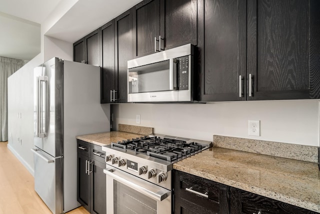 kitchen with light stone counters, stainless steel appliances, and light wood-type flooring