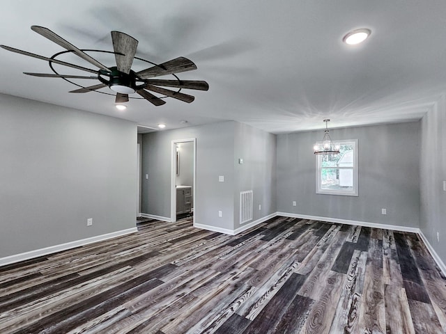 empty room with dark hardwood / wood-style flooring and ceiling fan with notable chandelier