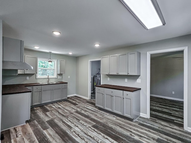 kitchen with butcher block countertops, sink, gray cabinetry, hanging light fixtures, and dark hardwood / wood-style flooring