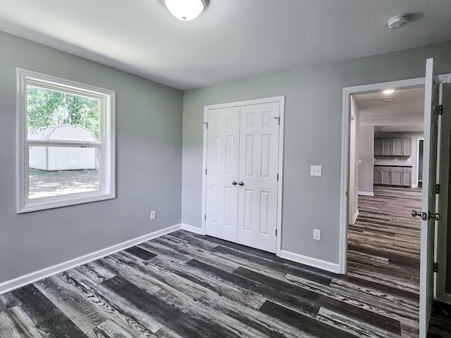 unfurnished bedroom with dark wood-type flooring and a closet