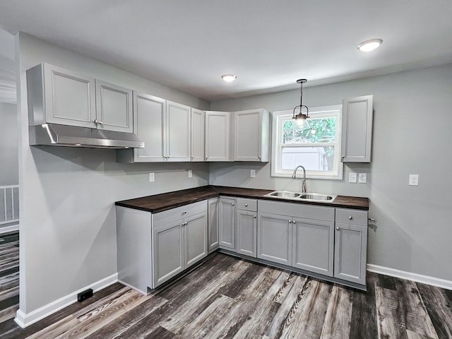 kitchen with dark wood-type flooring, butcher block counters, sink, decorative light fixtures, and gray cabinets