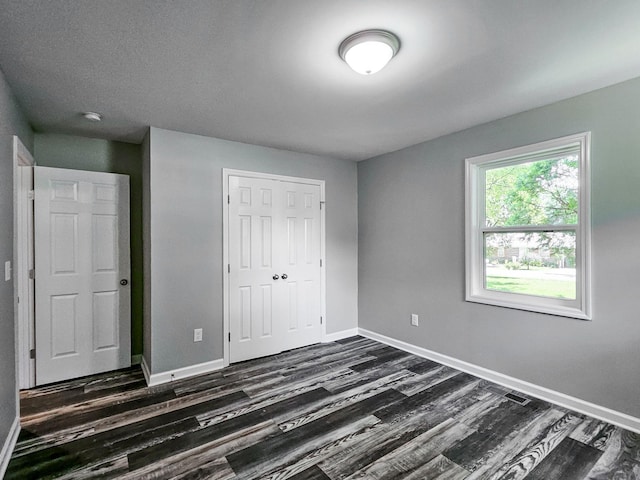 unfurnished bedroom with dark wood-type flooring and a closet