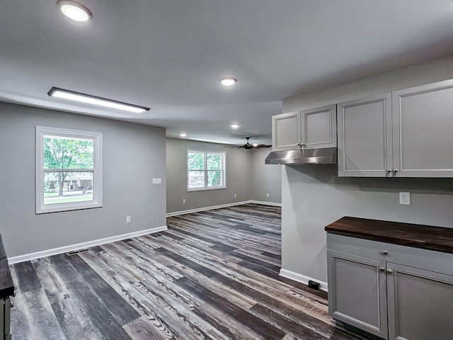 kitchen with gray cabinetry, dark wood-type flooring, wood counters, and ceiling fan