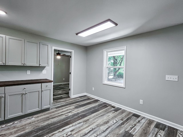 kitchen featuring gray cabinetry, dark hardwood / wood-style flooring, wood counters, and ceiling fan