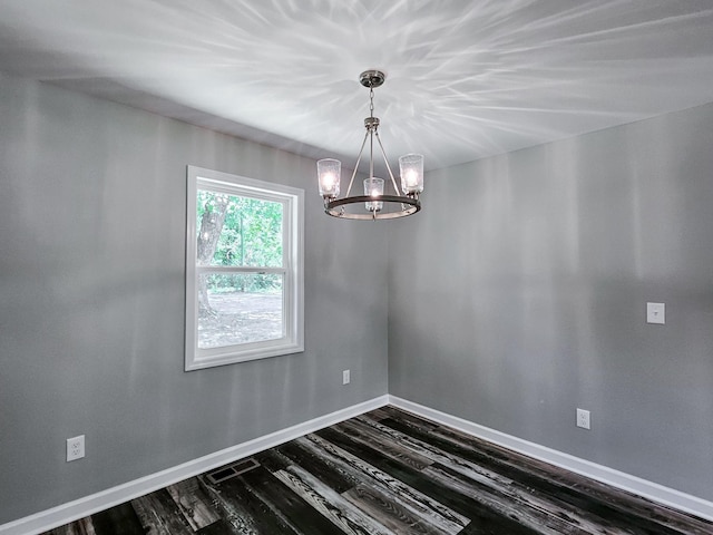 spare room featuring an inviting chandelier and dark hardwood / wood-style floors