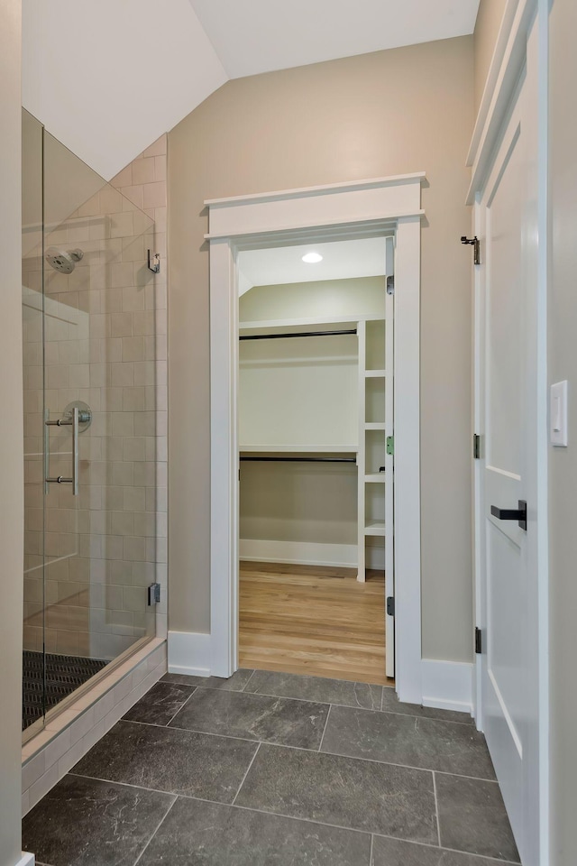 bathroom featuring lofted ceiling and a shower with shower door