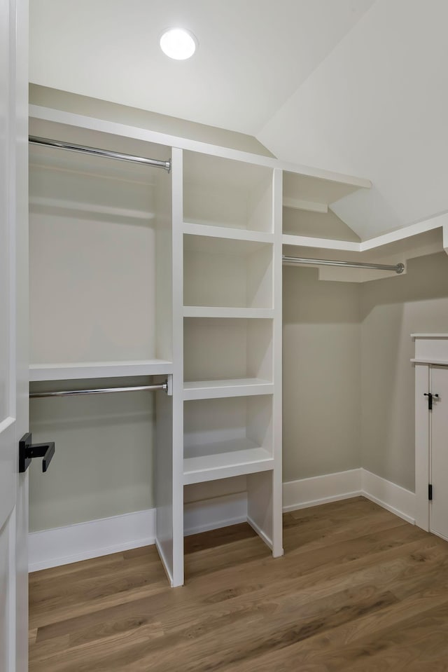 walk in closet with vaulted ceiling and hardwood / wood-style flooring