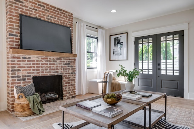 living room with hardwood / wood-style floors, a brick fireplace, and french doors