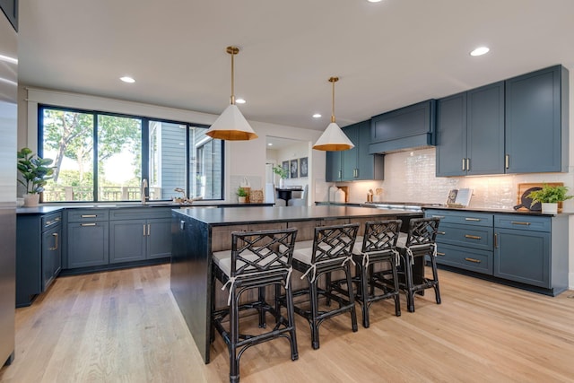 kitchen featuring hanging light fixtures, a kitchen island, light hardwood / wood-style floors, and blue cabinets