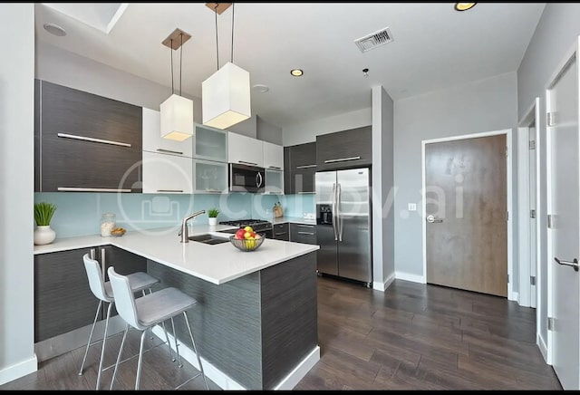 kitchen featuring hanging light fixtures, dark hardwood / wood-style flooring, a kitchen breakfast bar, kitchen peninsula, and stainless steel appliances