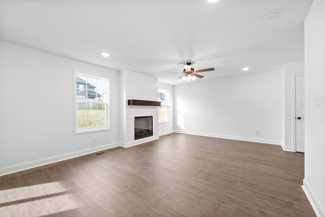 unfurnished living room with ceiling fan, dark hardwood / wood-style flooring, and a fireplace