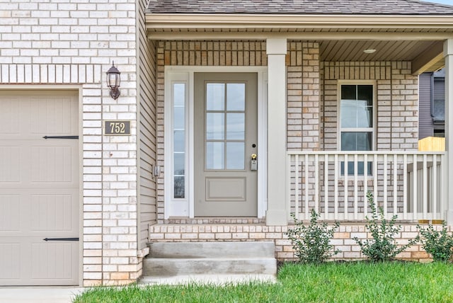 view of exterior entry featuring covered porch and a garage