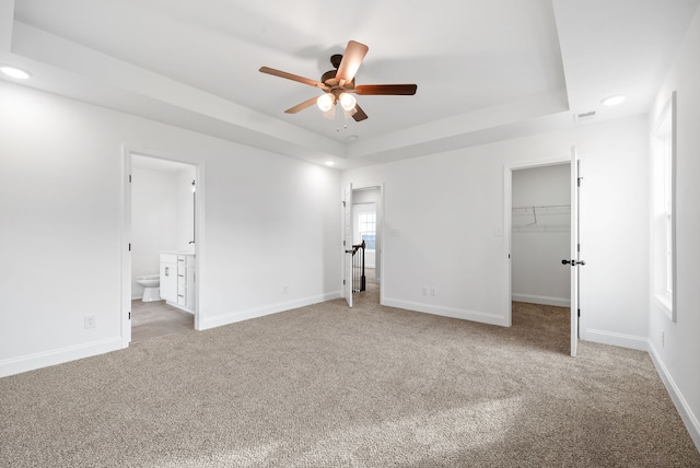 unfurnished bedroom featuring connected bathroom, ceiling fan, carpet floors, and a walk in closet