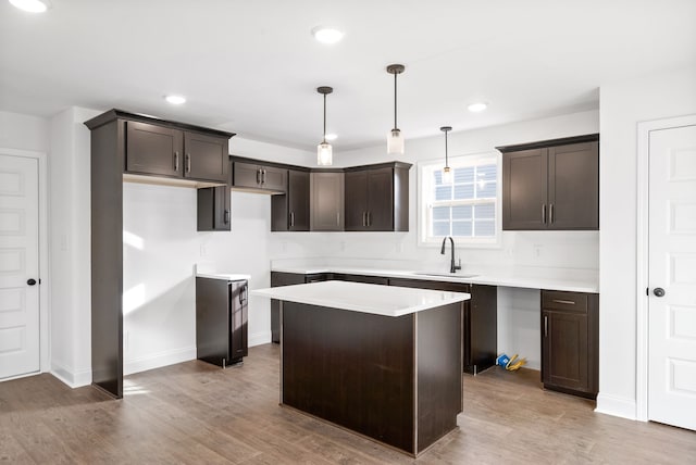 kitchen with sink, hanging light fixtures, light hardwood / wood-style floors, dark brown cabinets, and a kitchen island