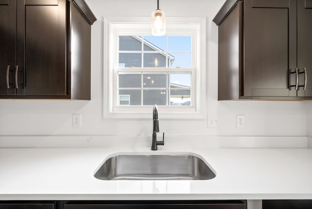 kitchen featuring dark brown cabinetry, hanging light fixtures, and sink