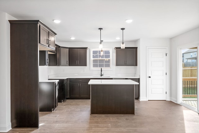 kitchen with sink, a kitchen island, a healthy amount of sunlight, and decorative light fixtures