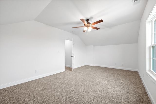 additional living space with ceiling fan, a healthy amount of sunlight, carpet floors, and vaulted ceiling