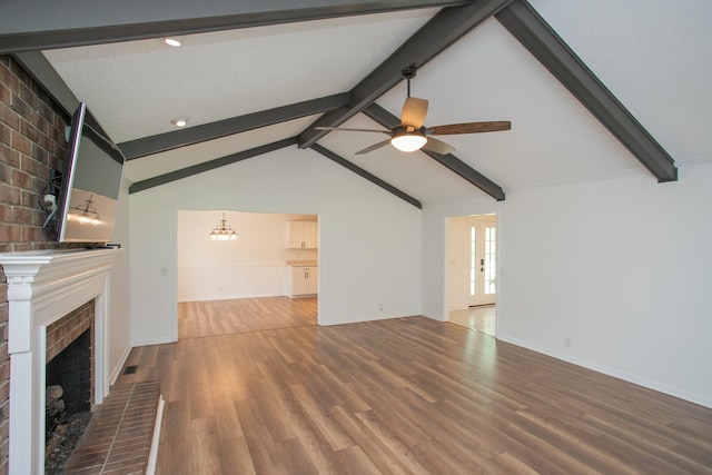 unfurnished living room with ceiling fan with notable chandelier, a fireplace, wood-type flooring, and lofted ceiling with beams